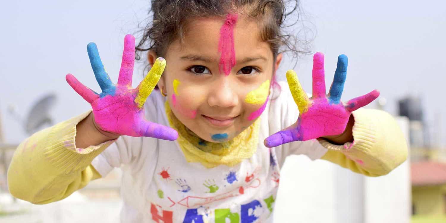 Petite fille avec les mains peintes en couleur qui sourit